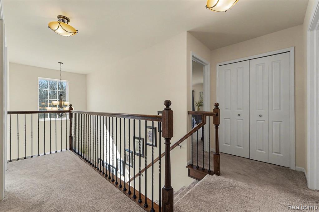 Corridor featuring carpet, an upstairs landing, and a chandelier