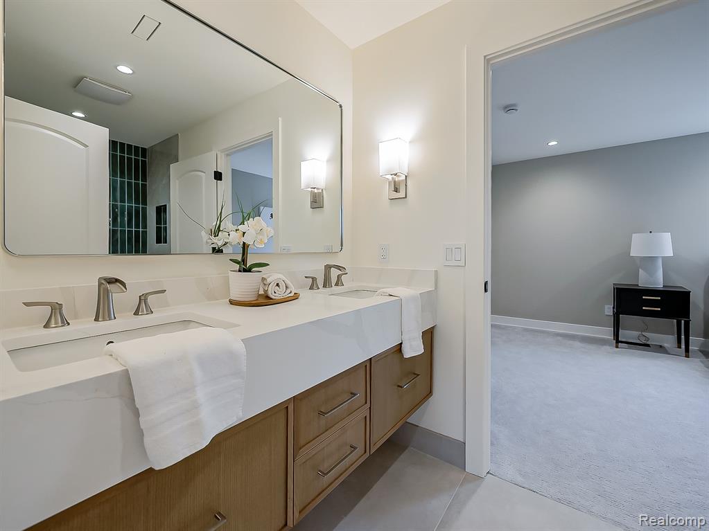 Bathroom with double vanity, light colored carpet, and recessed lighting