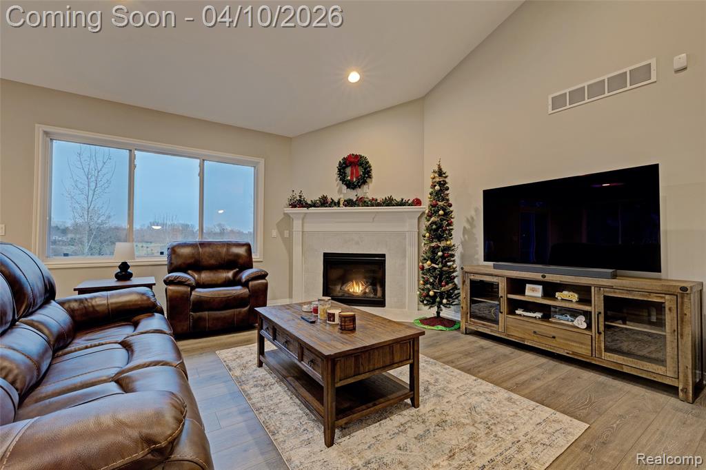 Living room with a fireplace, light wood-style floors, recessed lighting, and vaulted ceiling