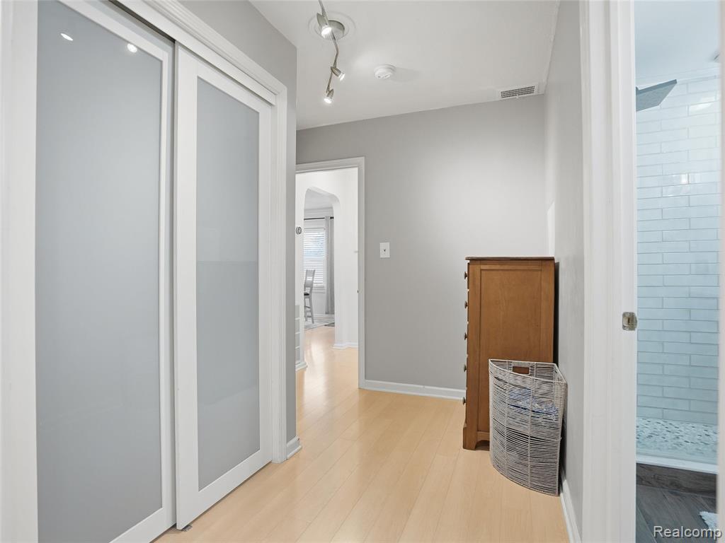 Corridor featuring arched walkways and light wood finished floors