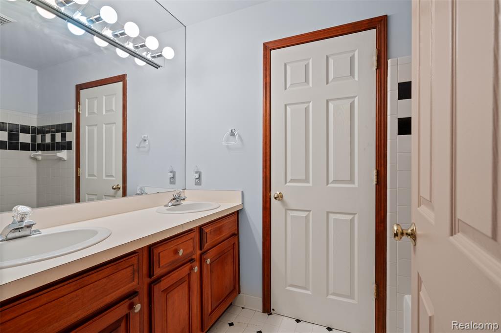 Full bath with double vanity and light tile patterned floors