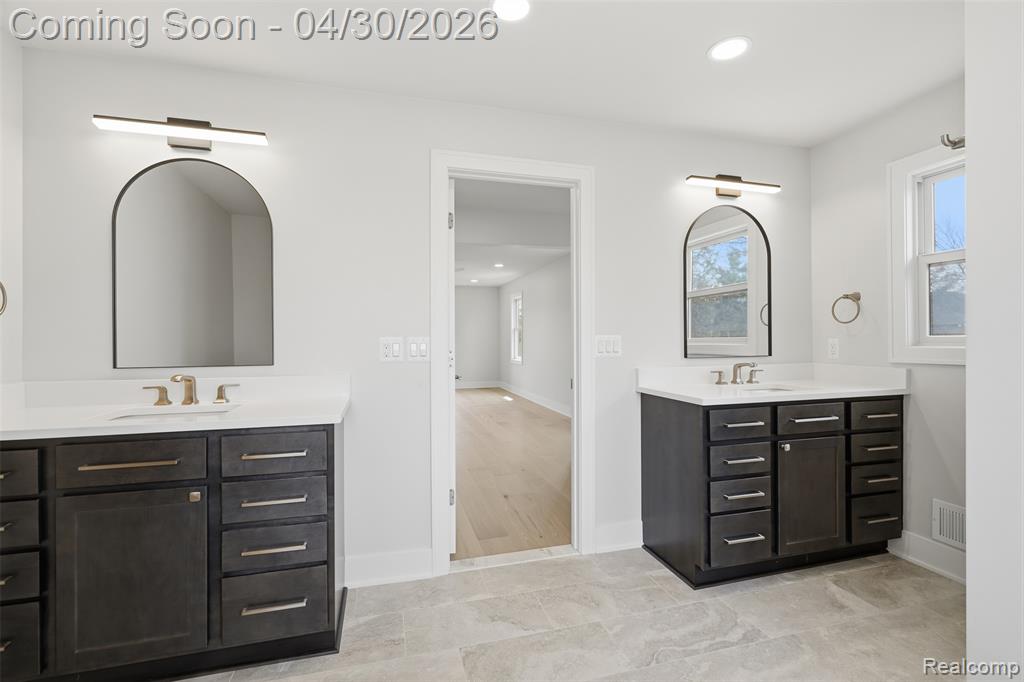 Primary bathroom with two separate vanities w/ recessed lighting