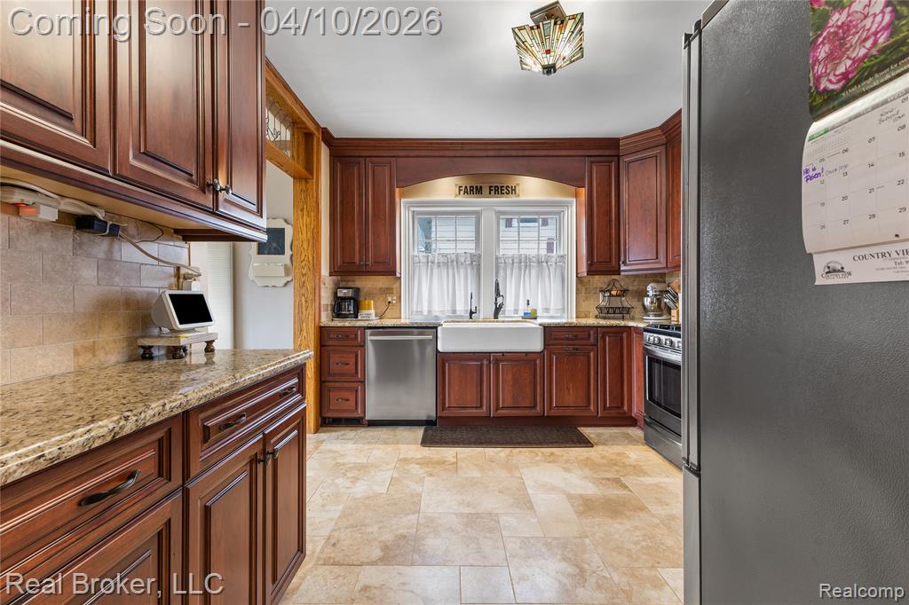 Kitchen with stainless steel appliances, light stone countertops, stone finish flooring, and backsplash