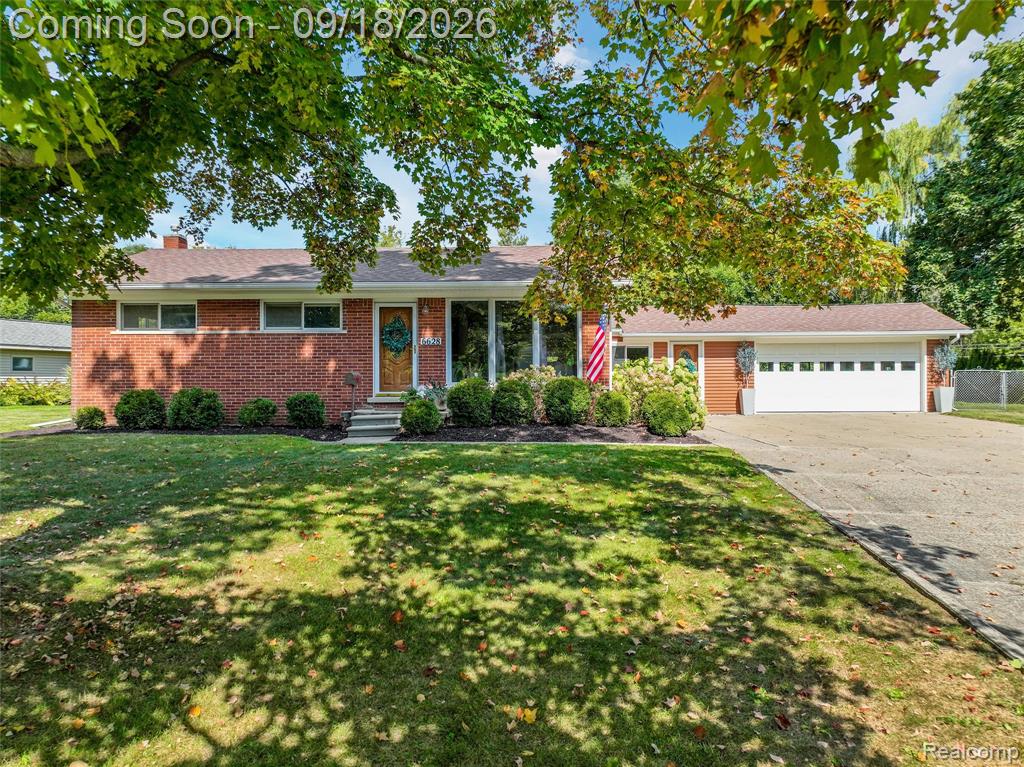 Brick-front exterior with mature landscaping, and a paved driveway