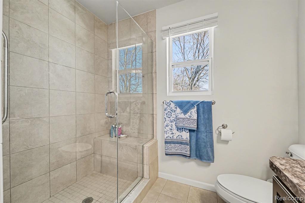 Full bathroom featuring vanity, a stall shower, and light tile patterned flooring