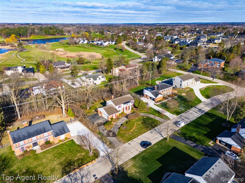 Aerial perspective of suburban area with a nearby body of water and a golf club