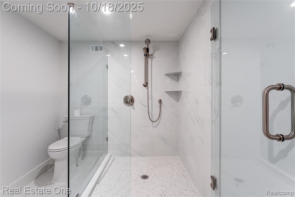 Full bathroom with toilet and a marble finish shower