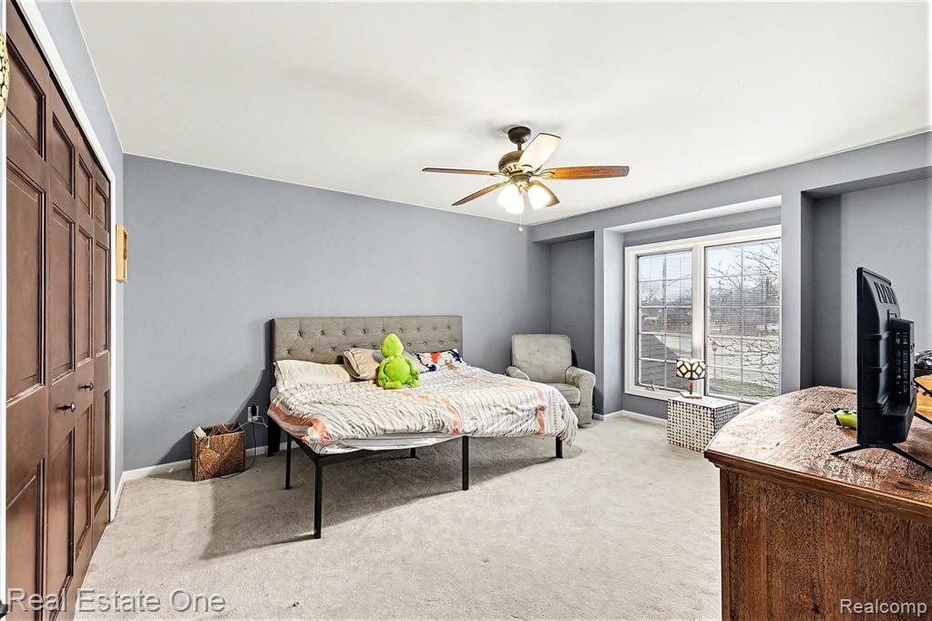 Bedroom with light carpet, a closet, and ceiling fan