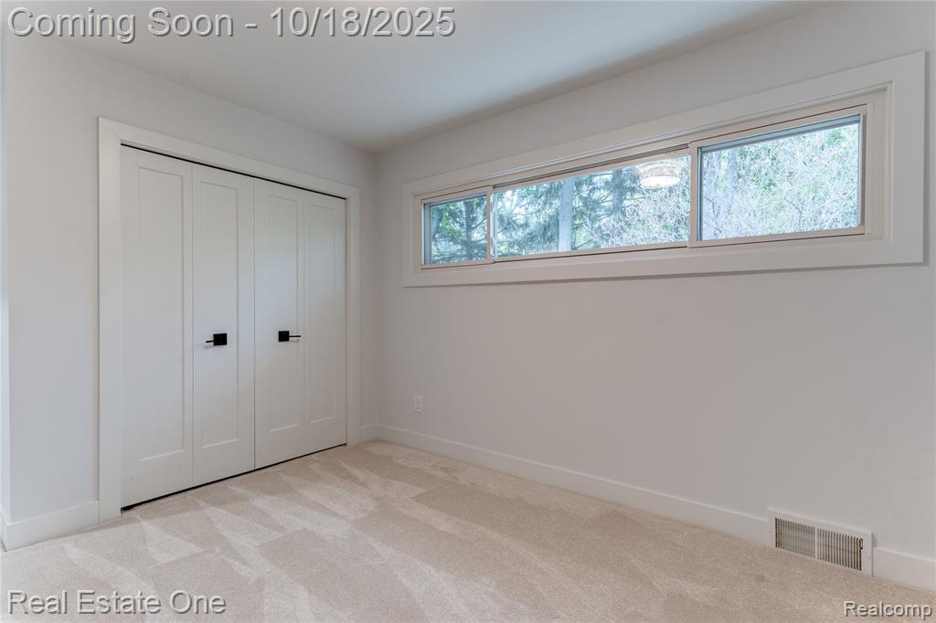 Unfurnished bedroom with light colored carpet and a closet