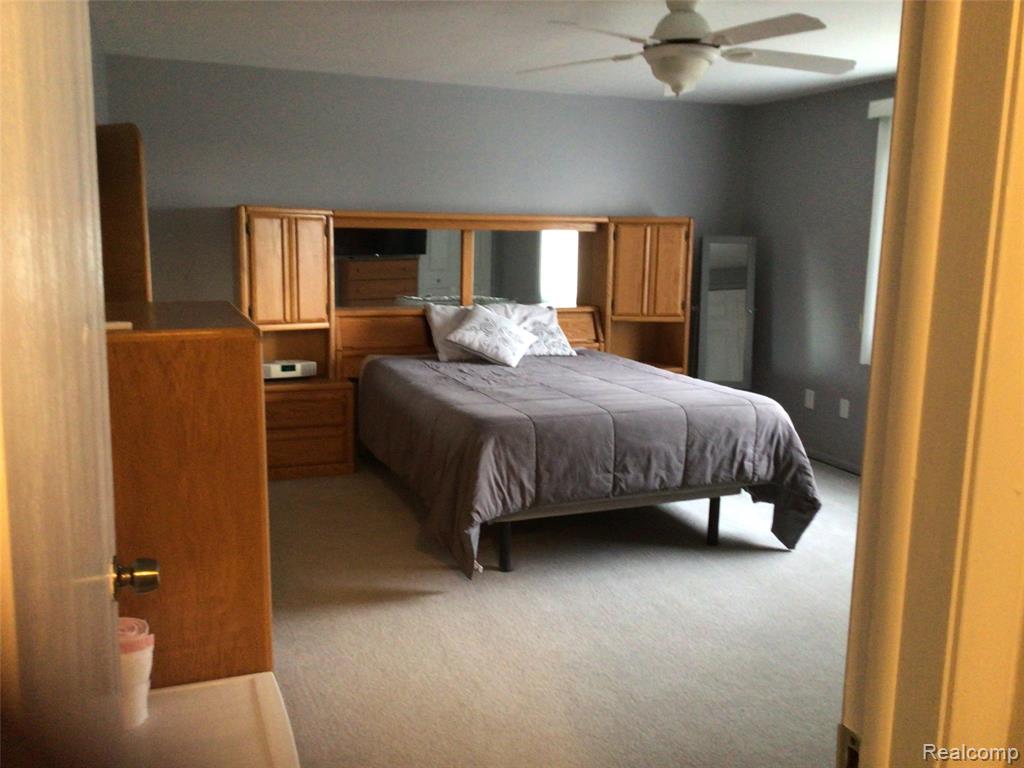 Bedroom with a ceiling fan and light carpet