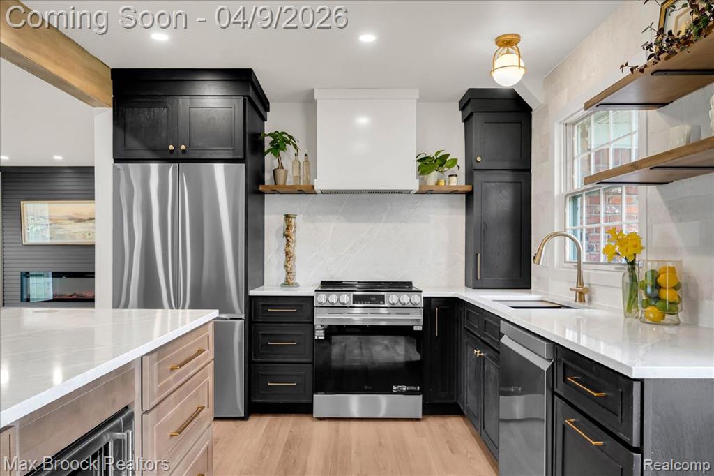 Dual tone kitchen featuring open shelves, light stone countertops, stainless steel appliances, light wood-type flooring, and two tone cabinetry