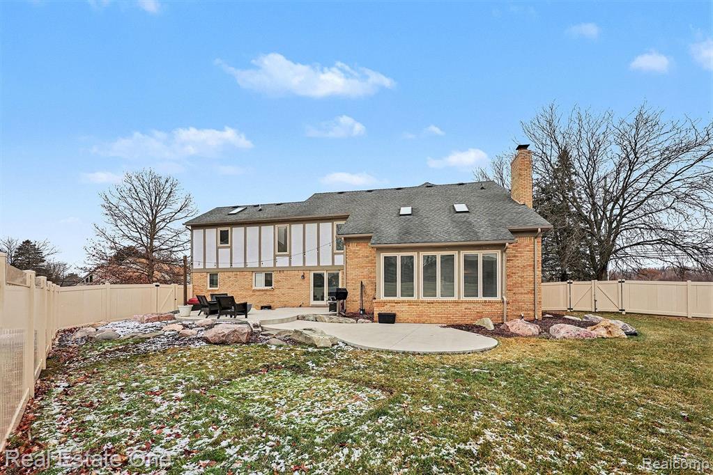 Rear view of house with a fenced backyard, a patio area, a chimney, and brick siding