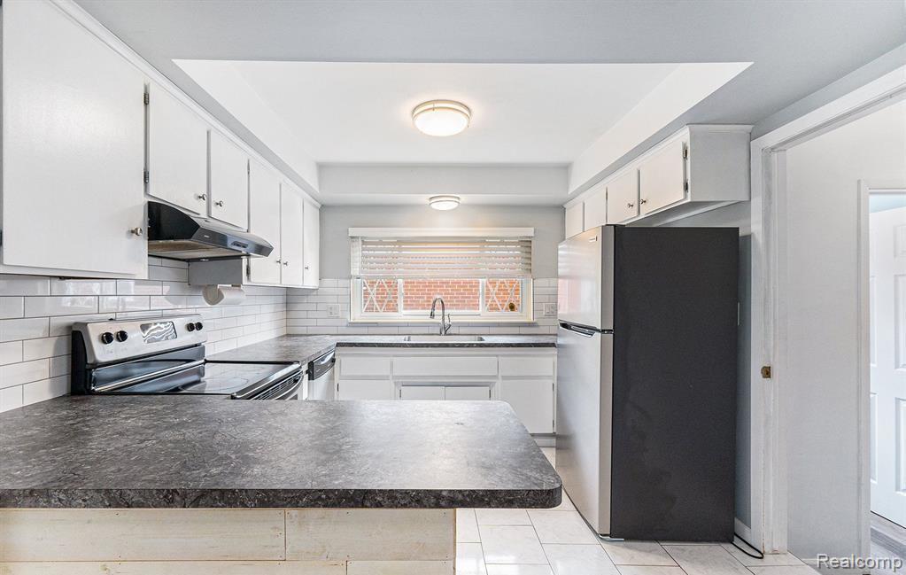 Kitchen with stainless steel appliances, white cabinets, dark countertops, and a peninsula