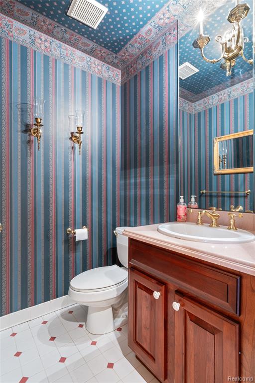 Bathroom with light tile patterned flooring, wallpapered walls, vanity, and a chandelier