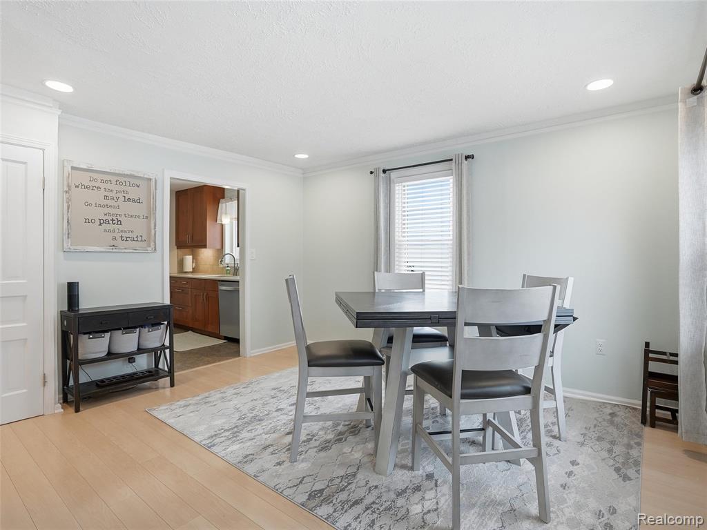 Dining space featuring light wood-style floors, crown molding, and recessed lighting