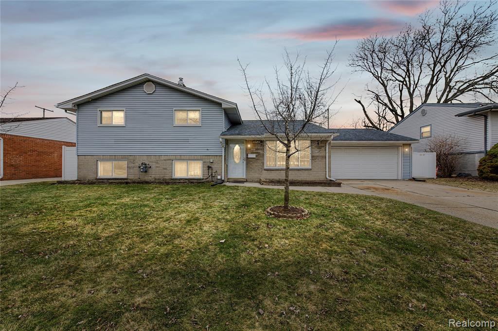 Tri-level home with driveway, a garage, and brick siding