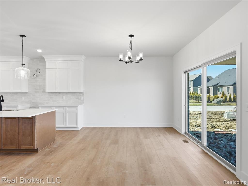 Unfurnished dining area with a chandelier and light wood-style flooring