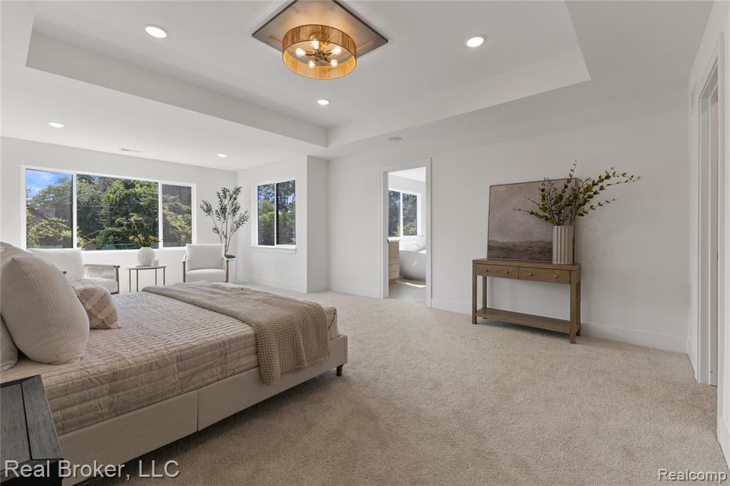 Bedroom featuring a raised ceiling, carpet floors, ensuite bath, recessed lighting, and a chandelier