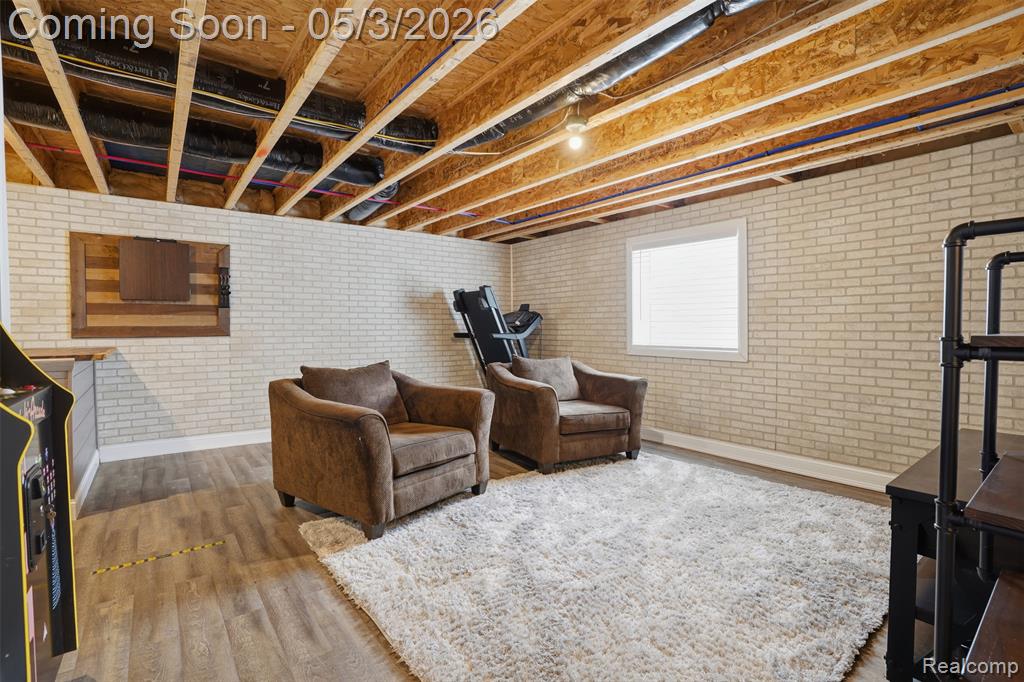 Finished lower level Living area featuring brick wall and wood finished floors