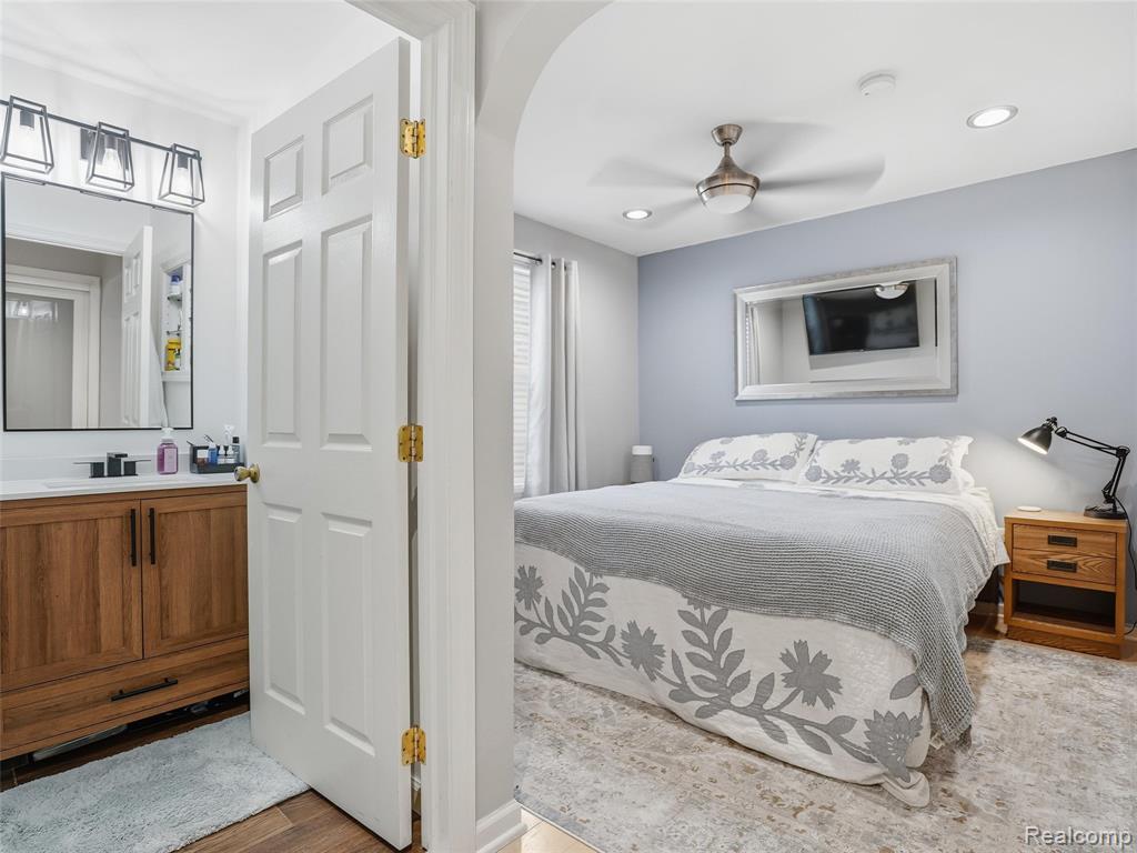 Bedroom featuring light wood-type flooring, ceiling fan, arched walkways, and recessed lighting
