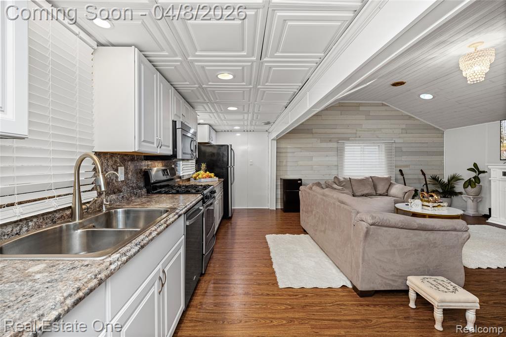 Kitchen with dark wood finished floors, white cabinetry, open floor plan, stainless steel appliances, and recessed lighting