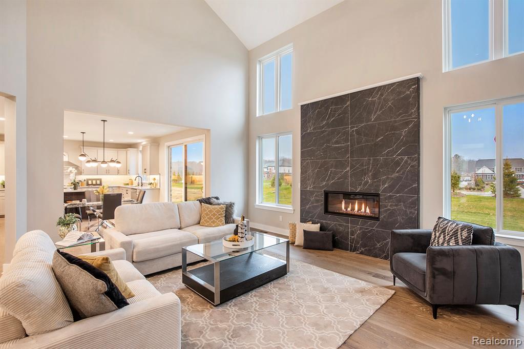 Living room with a premium fireplace, light wood-style flooring, and high vaulted ceiling