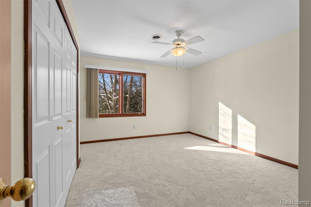 Unfurnished bedroom featuring light carpet, a closet, and a ceiling fan