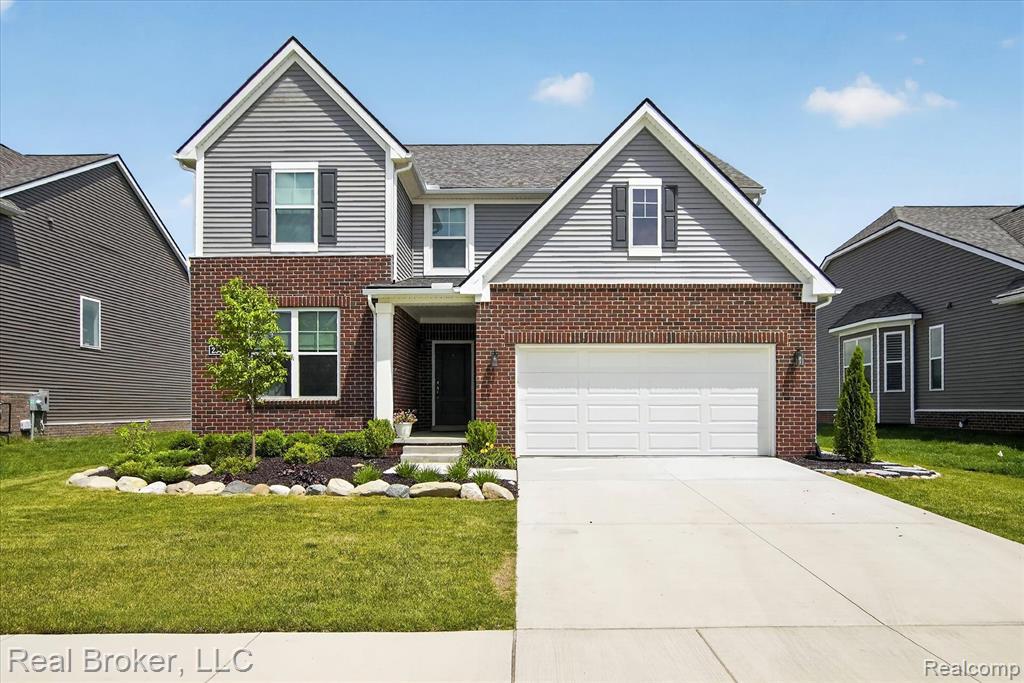 Contemporary two-story residence featuring brick and siding facade, a covered front entry, a two-car garage, and established front landscaping