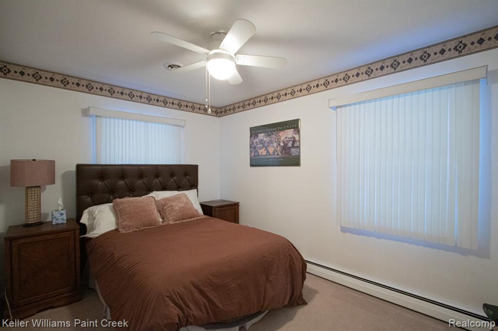 Carpeted bedroom with a baseboard heating unit and ceiling fan