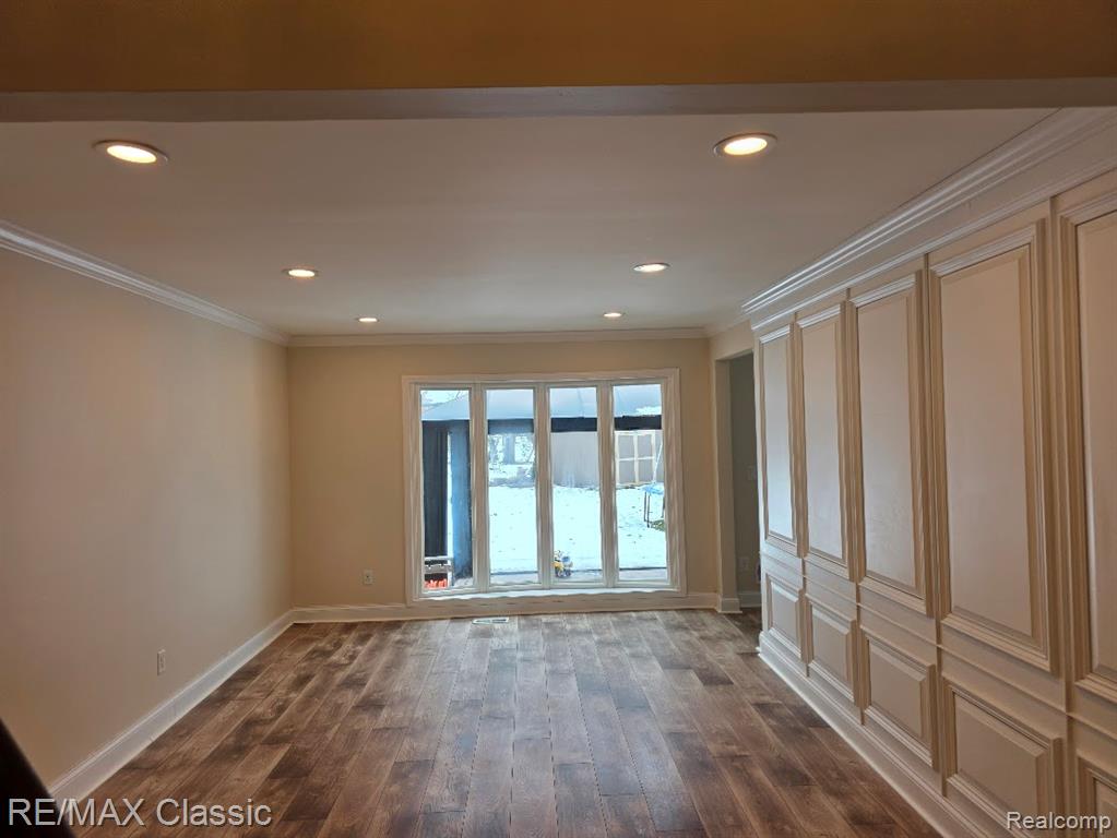 Unfurnished room with dark wood-style floors, crown molding, and recessed lighting