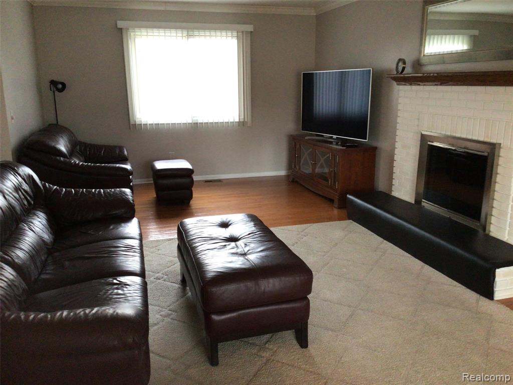 Living area featuring crown molding, wood finished floors, and a fireplace