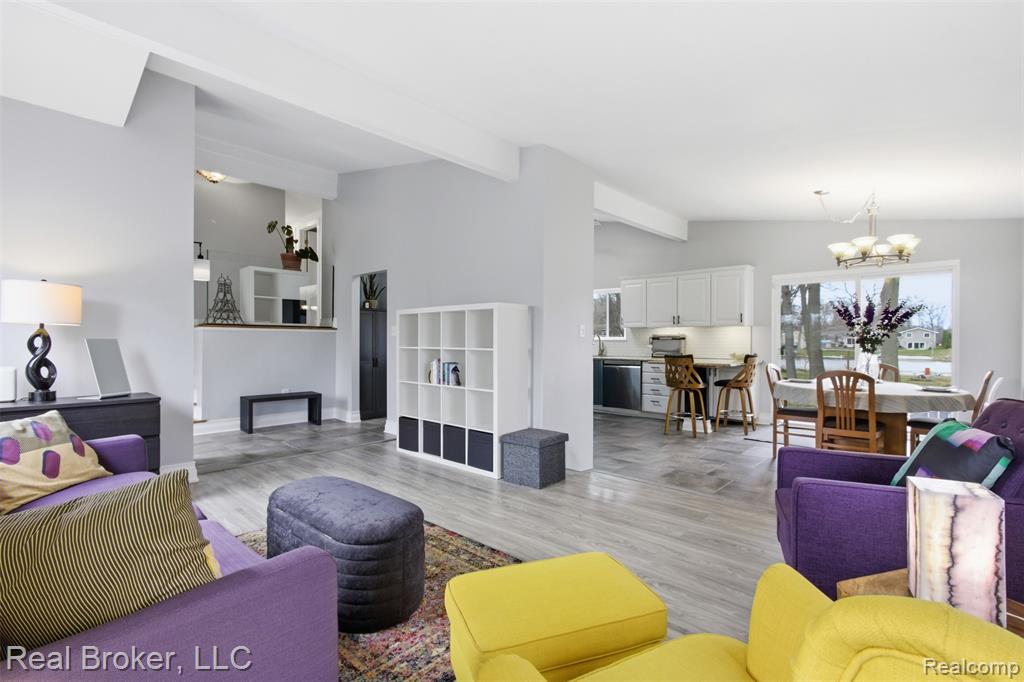 Living area with wood finished floors, hanging lights, and lofted ceiling with beams