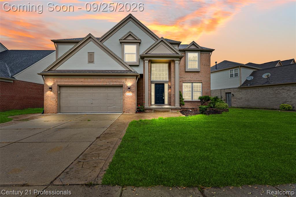 Brick and siding exterior with a two-car garage, concrete driveway, and front lawn