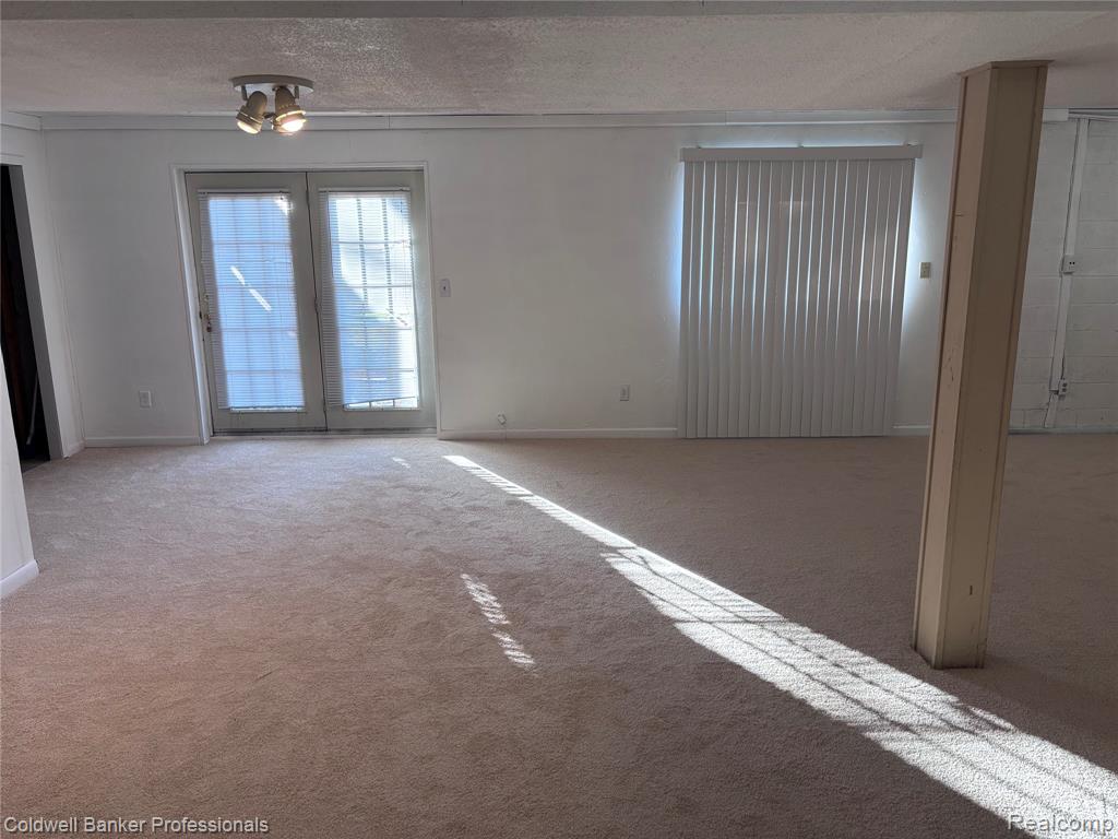 Empty room with a textured ceiling and carpet flooring