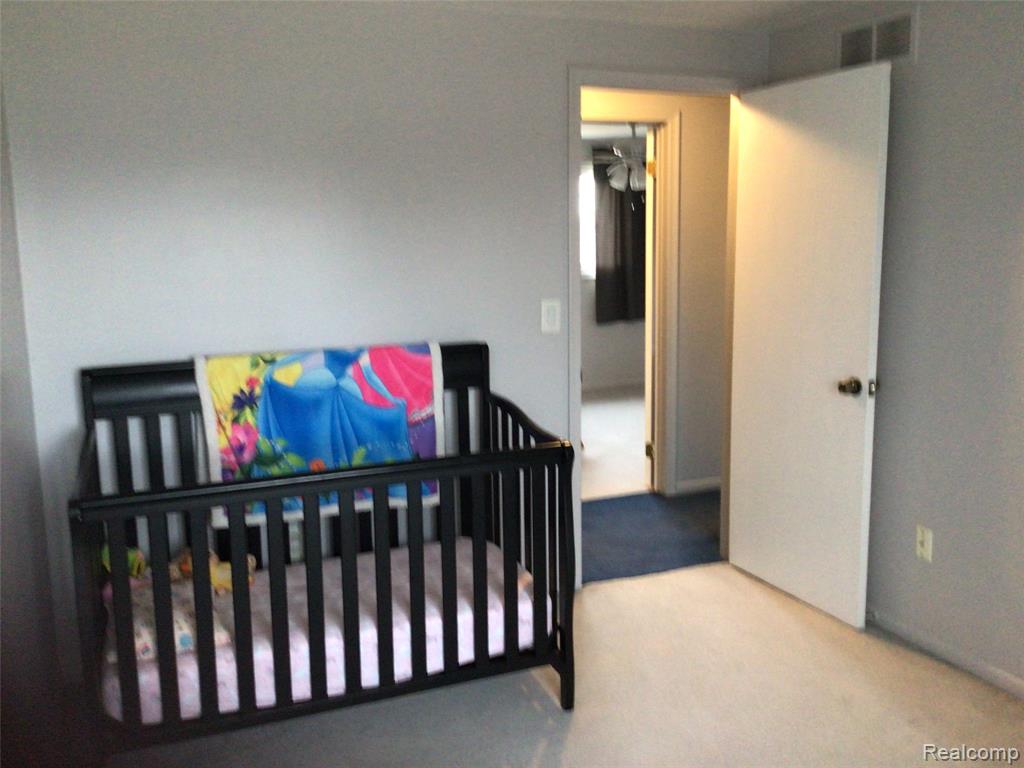Bedroom featuring a crib and light carpet