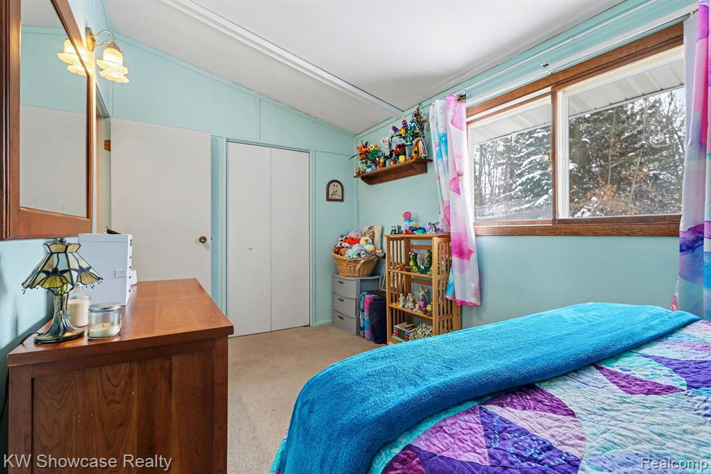 Bedroom featuring lofted ceiling, a closet, and light carpet