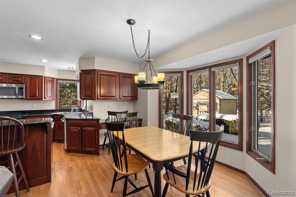 Dining area with light wood finished floors, a chandelier, and recessed lighting