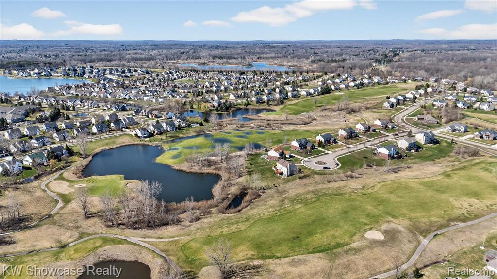 Aerial perspective of suburban area with a nearby body of water and a golf course