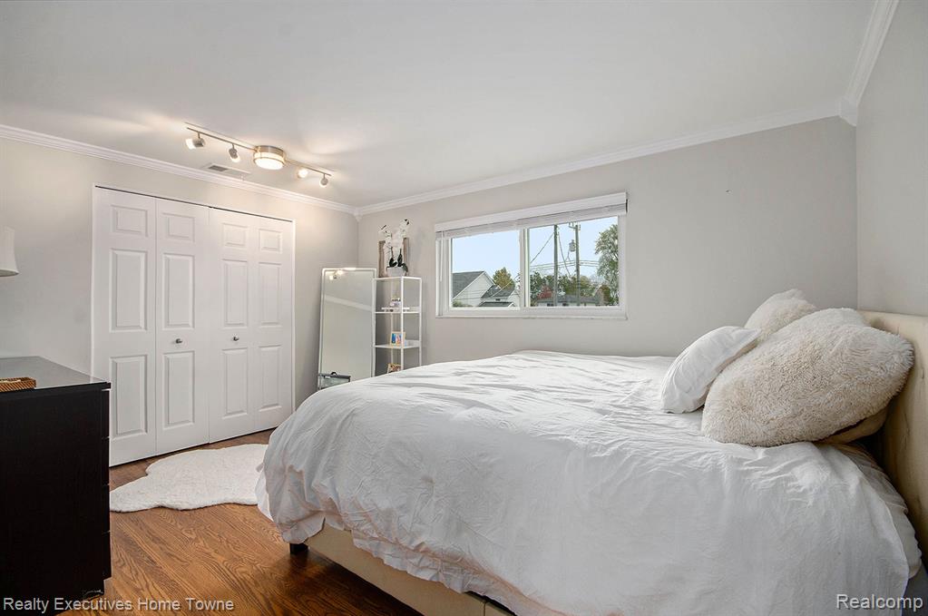 Bedroom with ornamental molding, dark wood-style flooring, and a closet