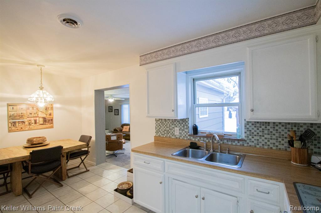 Kitchen with white cabinetry, backsplash, light countertops, and light tile patterned flooring