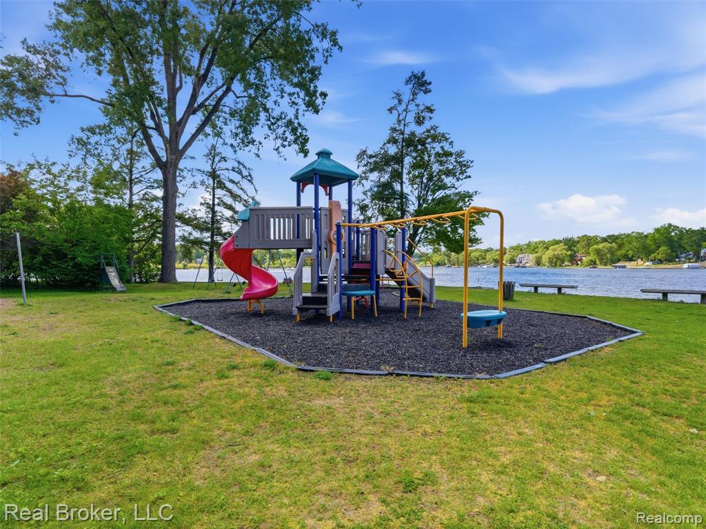 Playground area featuring a multi-level structure with slides and climbing elements, set on a rubberized surface