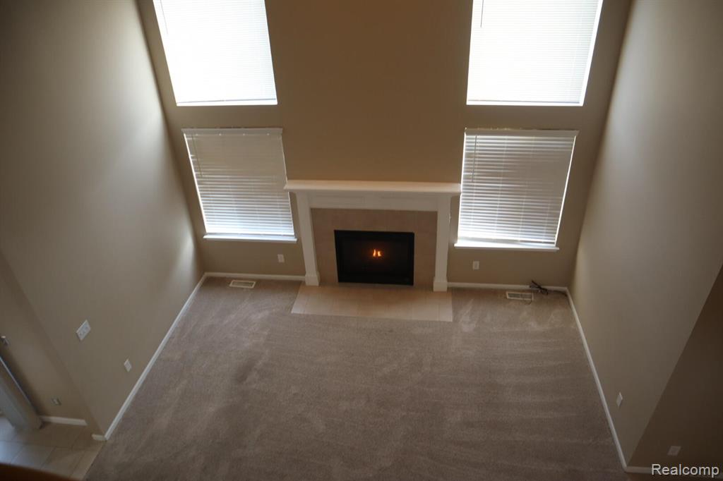 Unfurnished living room with a fireplace with flush hearth, ceiling fan, and dark carpet