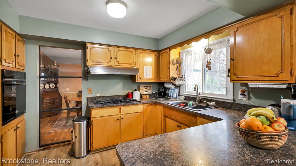 Kitchen with dark countertops, black appliances, light wood-style flooring, and wood finish cabinetry