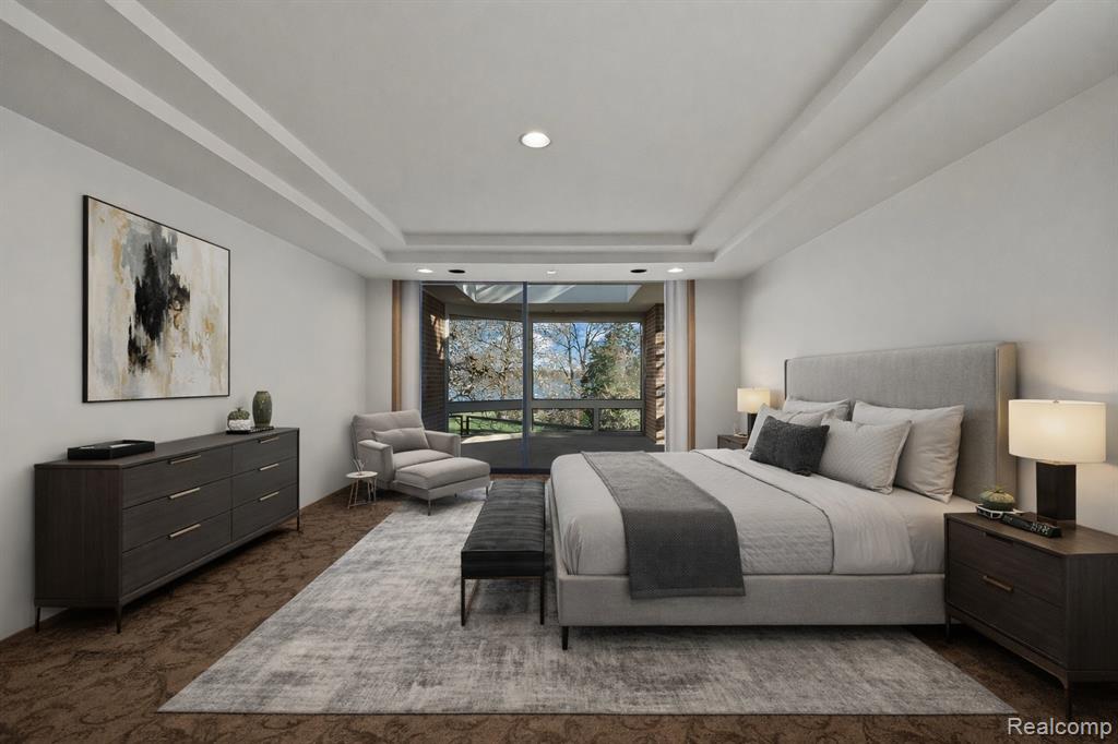 Bedroom with a raised ceiling, dark carpet, and recessed lighting