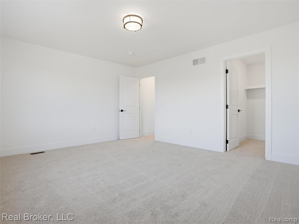 Unfurnished bedroom with light colored carpet and a walk in closet