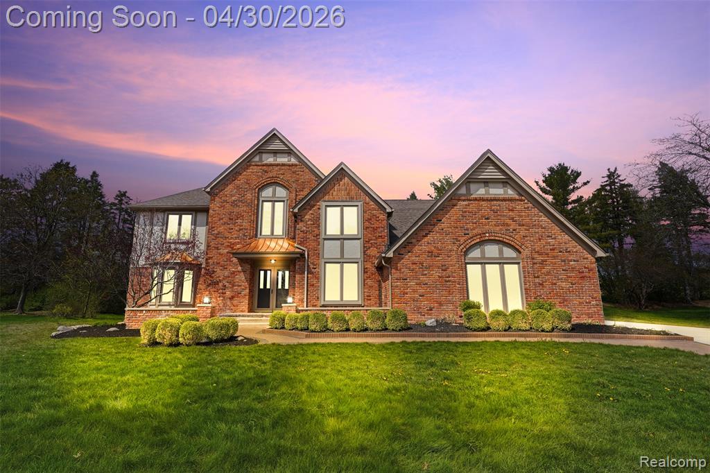 View of front of home with a lawn and brick siding