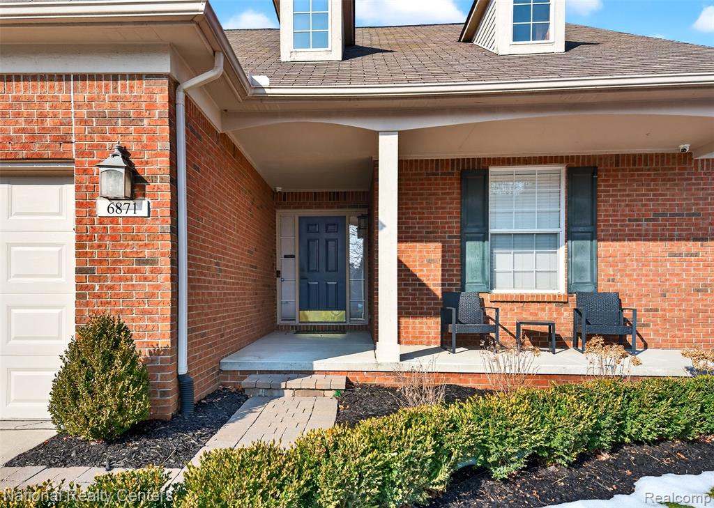 Doorway to property with a porch and brick siding