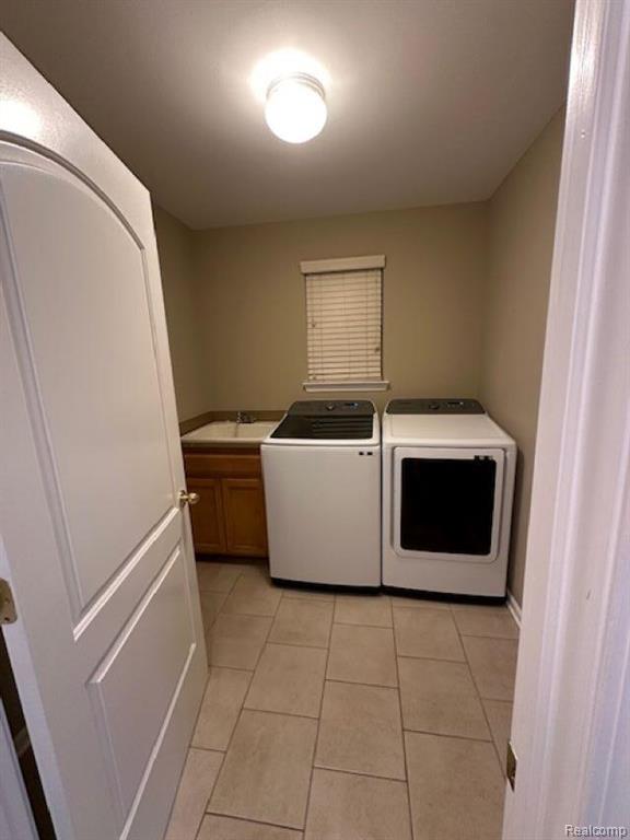 Laundry room featuring washer and clothes dryer, light tile patterned floors, and cabinet space