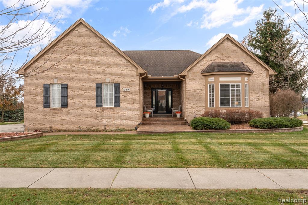 View of front of home featuring roof with shingles, brick siding, and a front yard