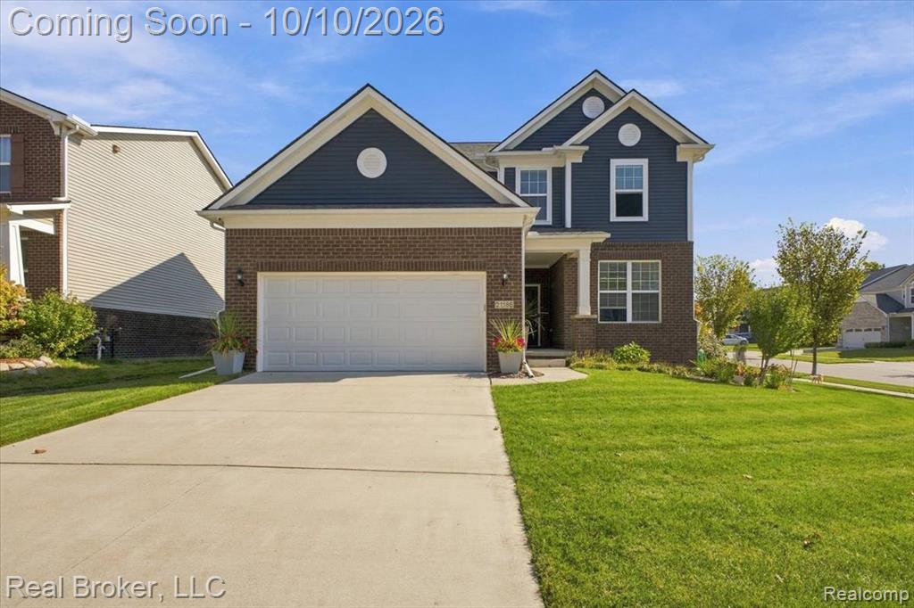 Two-story exterior featuring brick and siding finishes, an attached garage, a covered front entry, and a concrete driveway